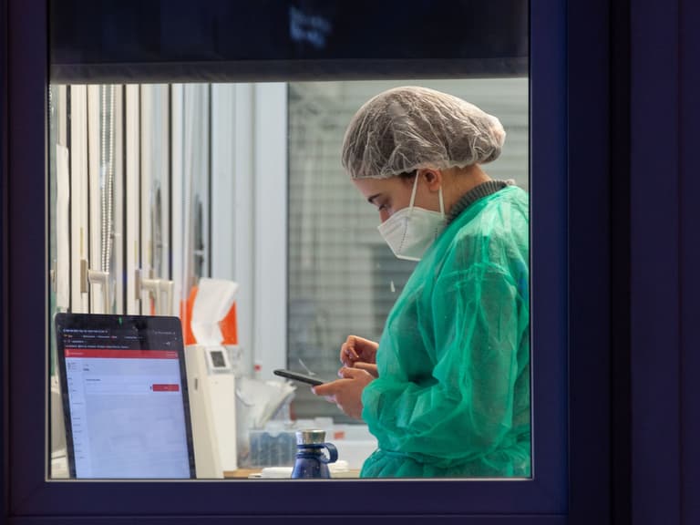 Professionnelle de laboratoire en tenue de protection consultant son téléphone à un poste de travail